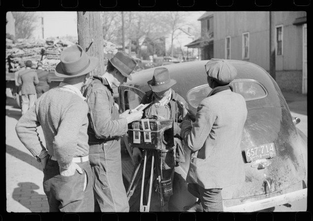 Travelling photographer making a sale outside warehouse where tobacco auctions are being held. Durham, North Carolina. Marion Post Wolcott, November 1939. 