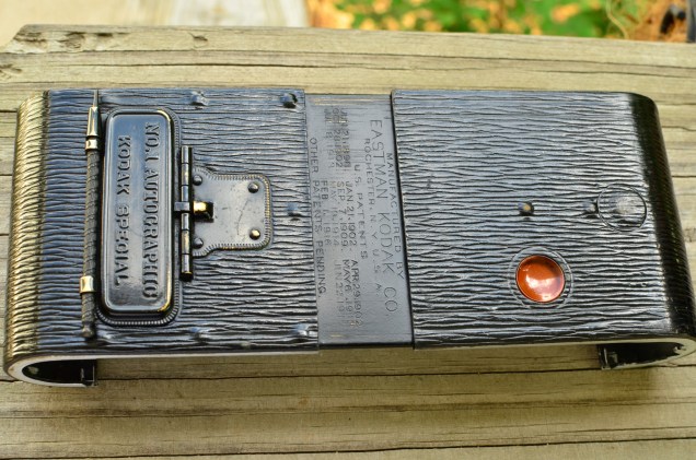 Various patent dates are etched into the case when you slide it open.  Also notice the large round protrusion above and to the right of the red window, this is what you press to open the camera.